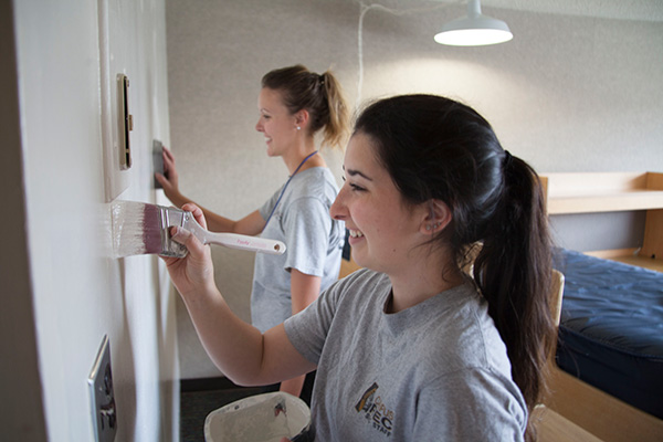 students paint wall in residence hall