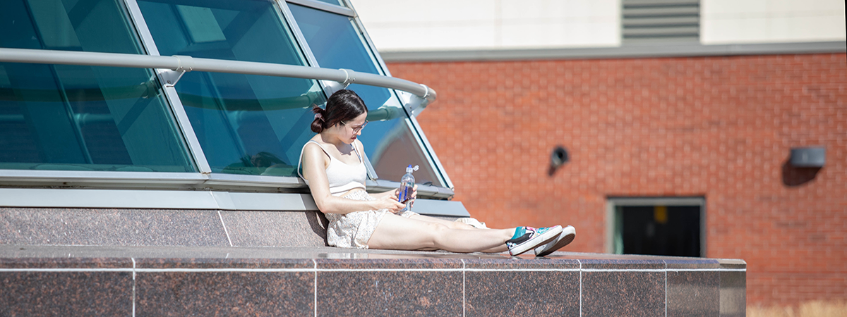 student sits by library roof